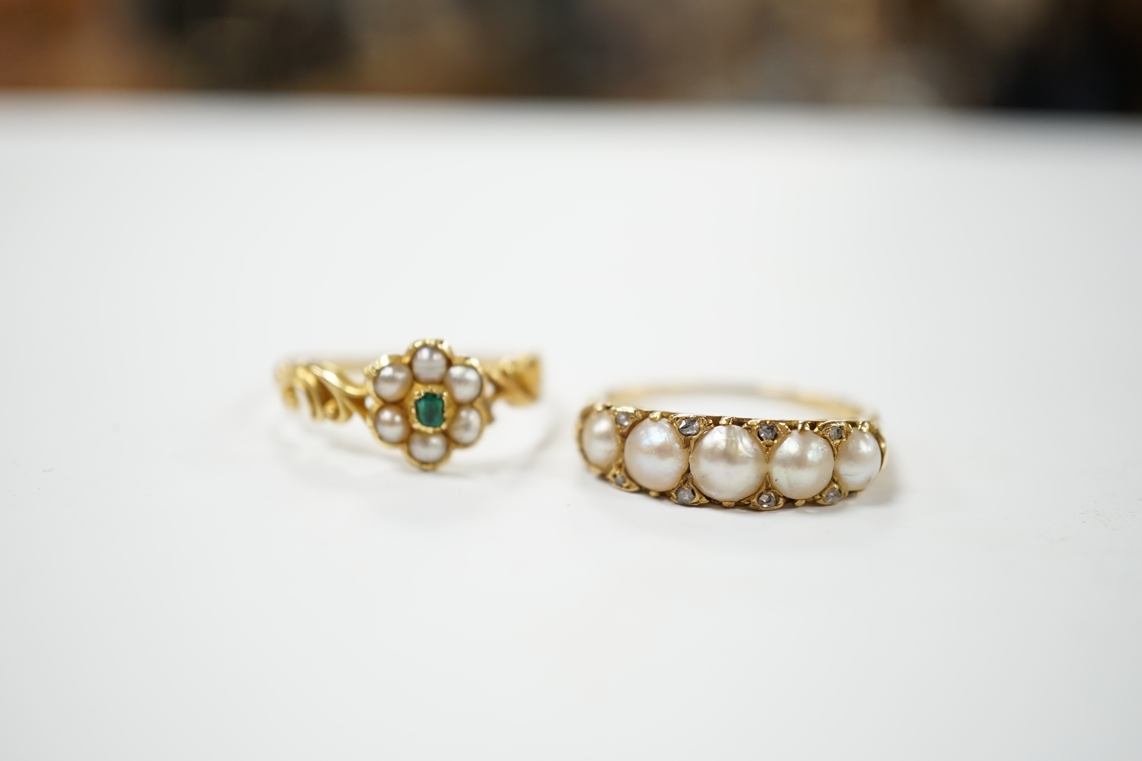 A yellow metal and graduated split pearl set half hoop ring with diamond chip spacers, size Q and a similar emerald and seed pearl flower head cluster ring, gross weight 5.7 grams. Condition - fair